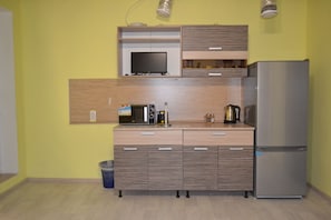 Een koelkast, een microgolfoven, kookgerei, borden en bestek