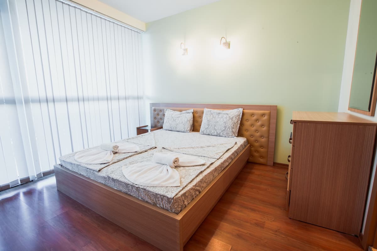 A neatly made bed with a headboard, a wooden nightstand, and a small cabinet.