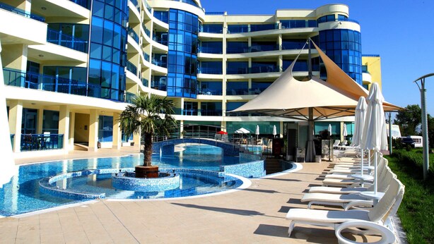 A hotel with a swimming pool, sun loungers, and a covered area with umbrellas. - Aparthotel Marina Holiday Club & Spa (Pomorie)
