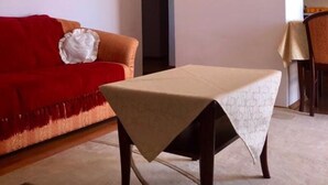 A living room with a red sofa, a small table with a white tablecloth, and a dark wooden coffee table. - Apartments Adriana (Tar-Vabriga)