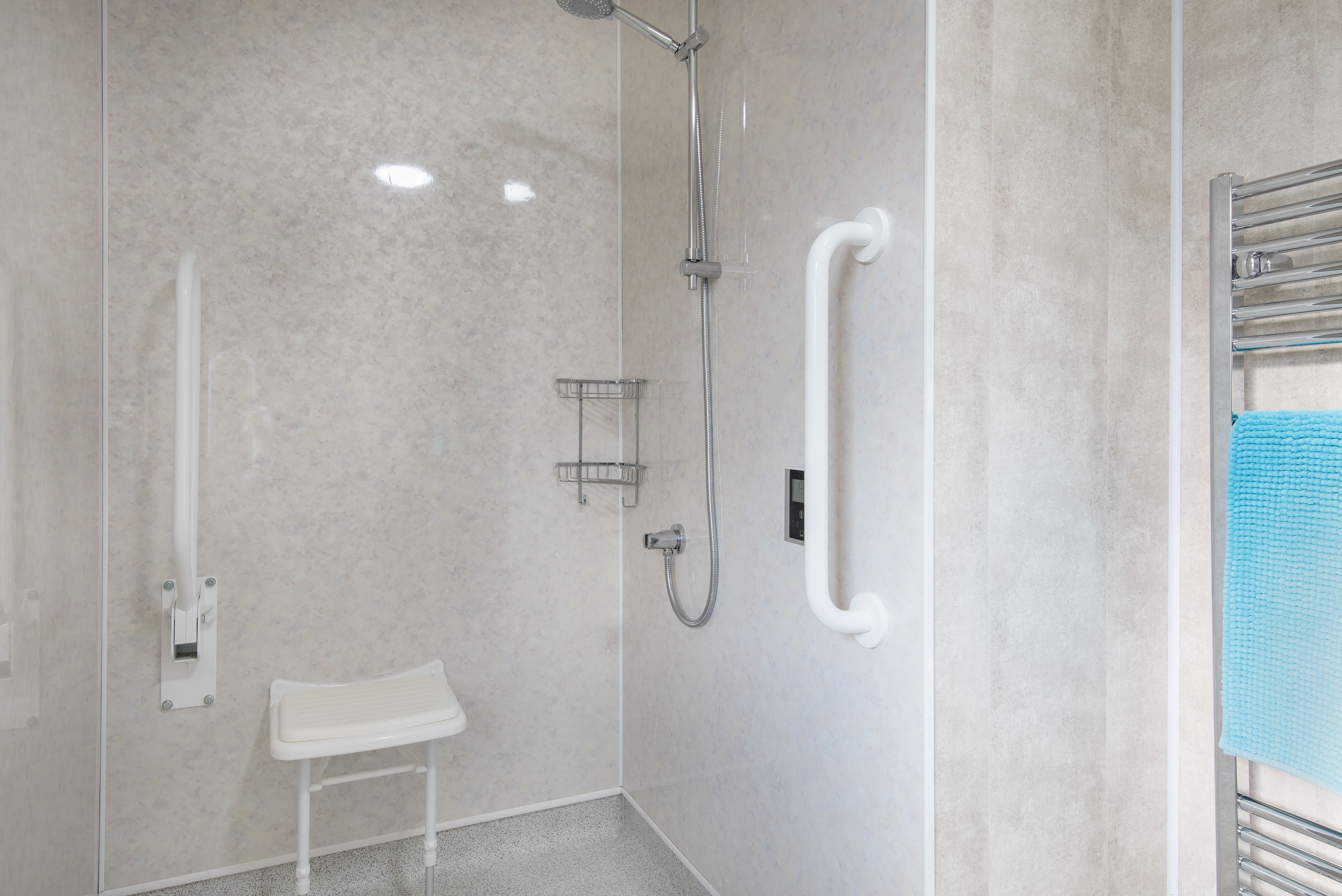 A modern bathroom with a walk-in shower, grab bars, and a small white bench.
