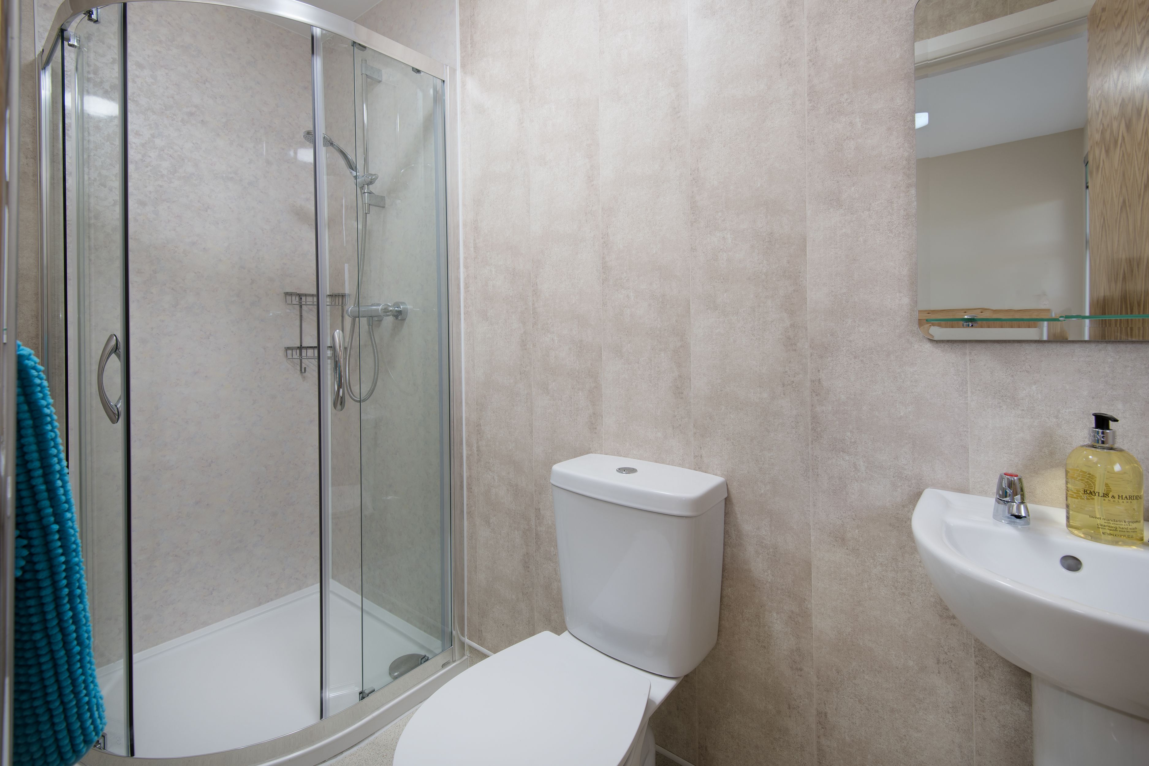 A bathroom with a glass-enclosed shower, a white toilet, and a sink with a mirror above it.