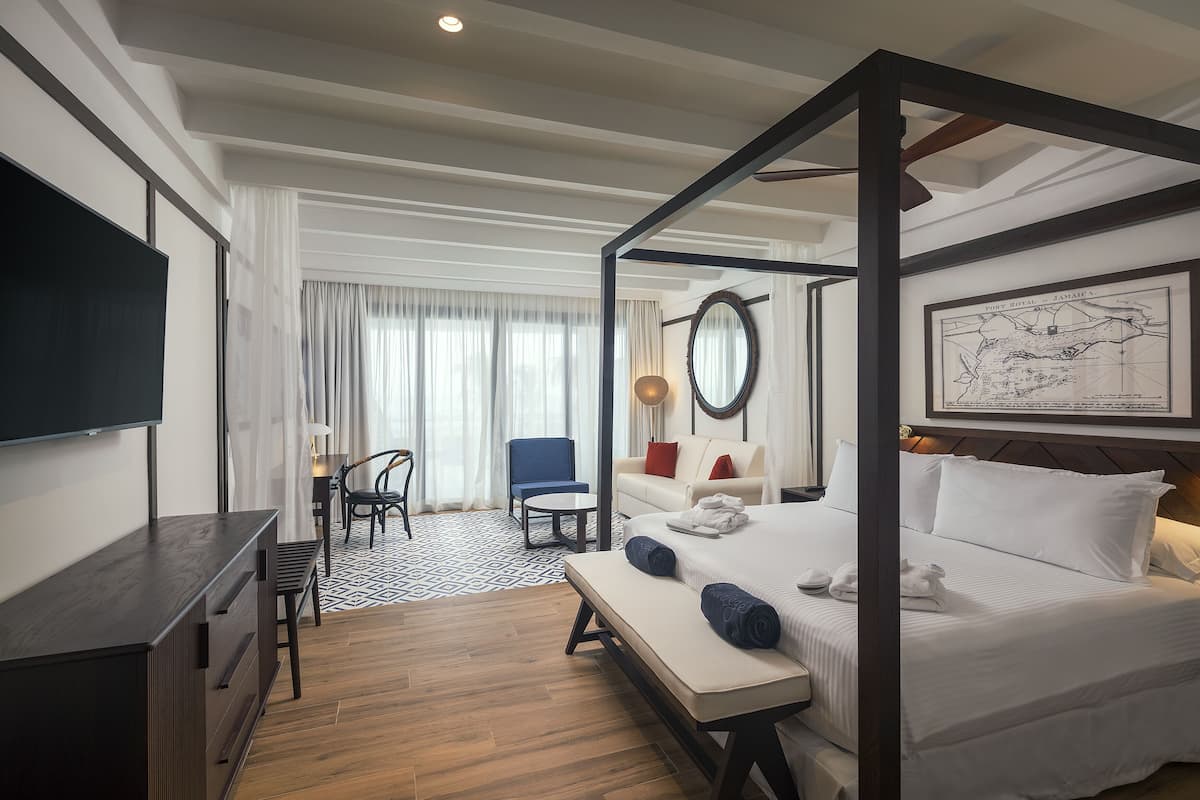 Habitación de hotel con cama con dosel, escritorio, silla, sofá y un mapa grande en la pared.