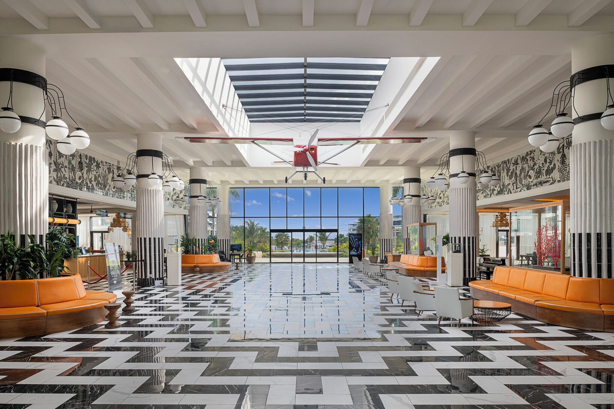 A spacious lobby with a geometric patterned floor, large windows, and a central ceiling feature.