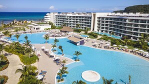 A resort with a large swimming pool, multiple hotel buildings, and a view of the ocean.
