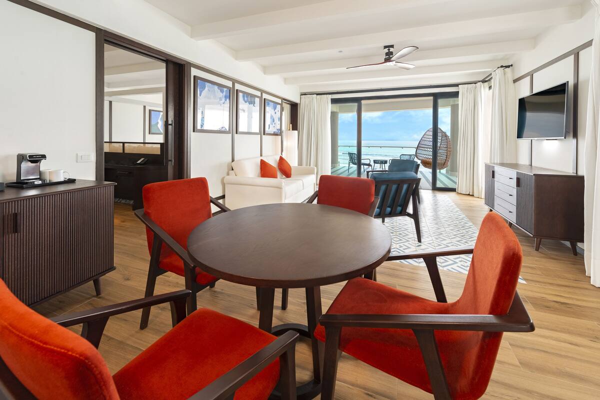 Una habitación moderna con una mesa redonda, sillas rojas, un sofá y un televisor.