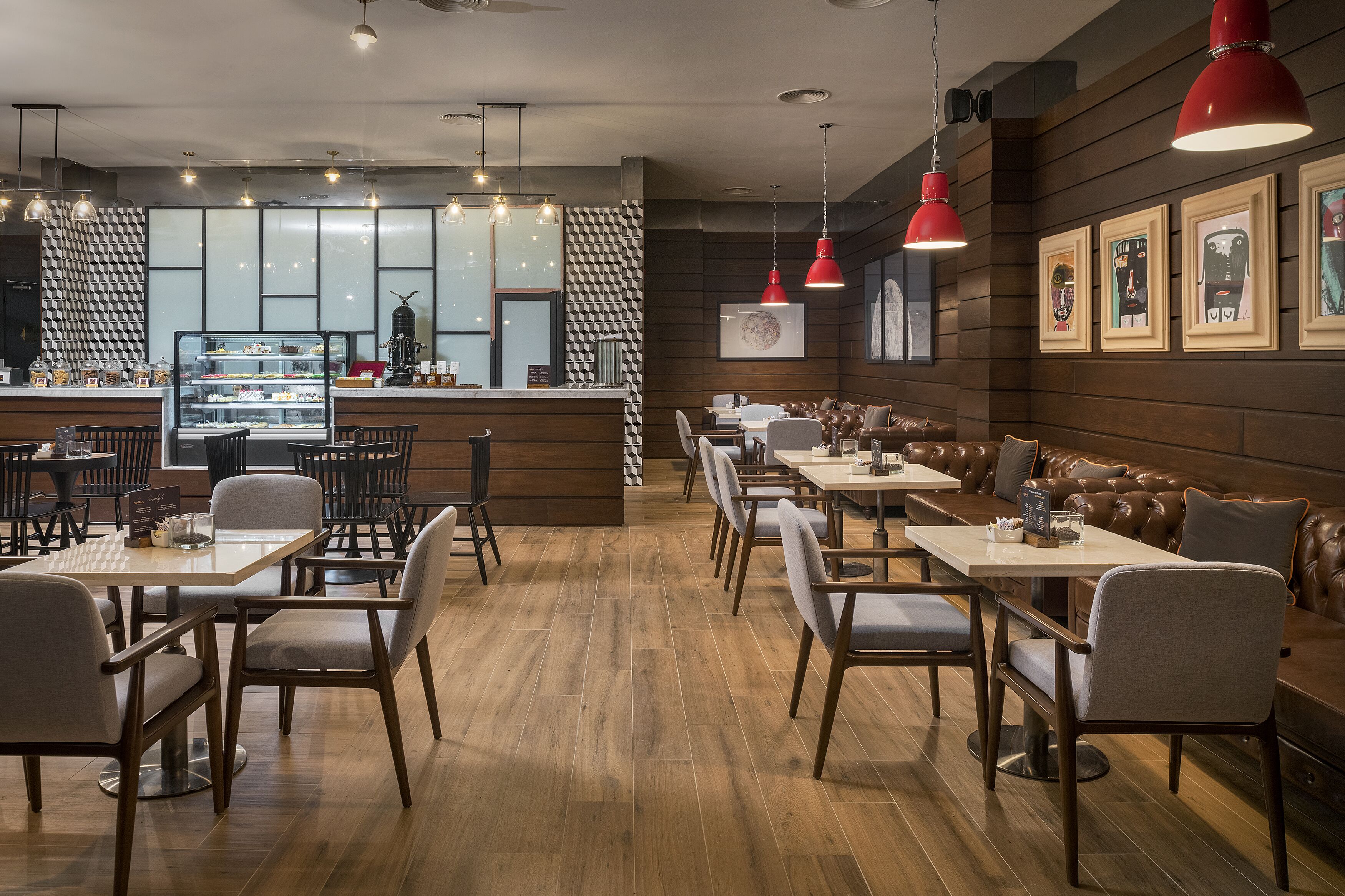 A modern restaurant interior with wooden flooring, leather booths, and red pendant lighting.