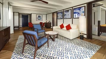 Un vaste espace de vie agrémenté d’un tapis à motifs, d’un canapé blanc avec des coussins rouges et d’un coin repas avec des chaises rouges.