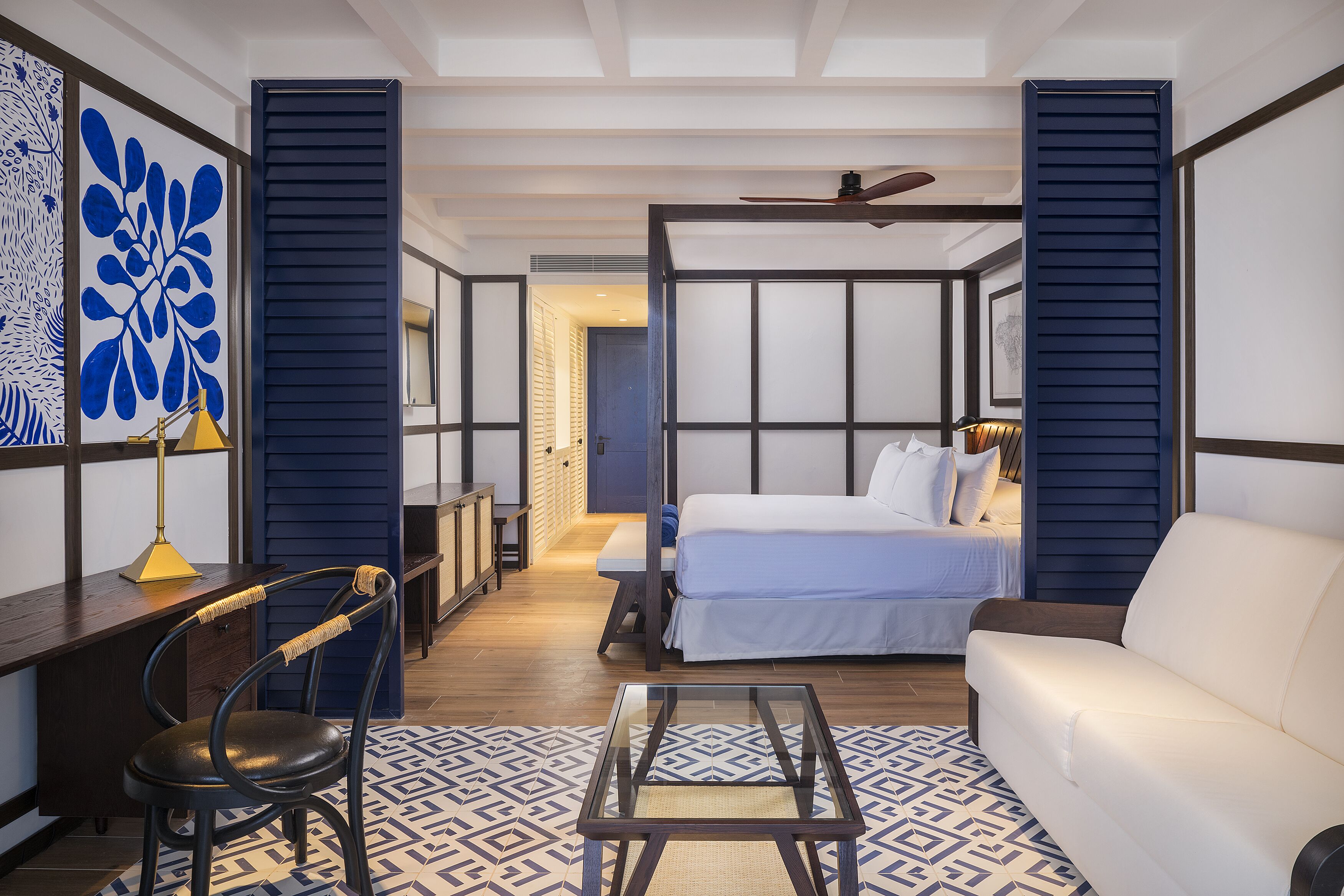 Quarto de hotel moderno com cama, sofá, escrivaninha e cadeira.