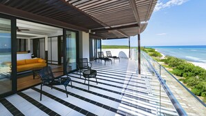 Um pátio moderno ao ar livre com piso de azulejos preto e branco, teto de madeira e vista para o oceano.