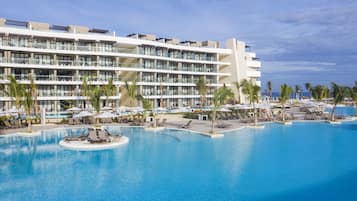 A hotel with a large pool, multiple balconies, and palm trees.