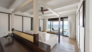 Quarto de hotel moderno com uma cama grande, varanda com vista para o mar e ventilador de teto.