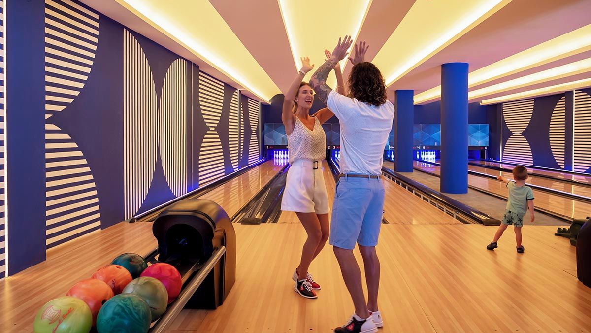 A bowling alley with multiple lanes, a bowling ball return area, and a modern design with geometric patterns on the walls.