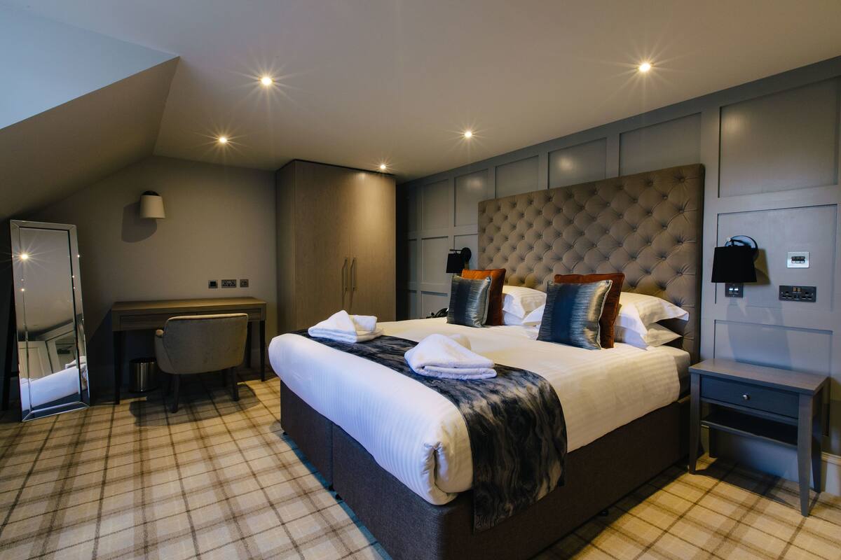 A modern hotel room with a large bed, a desk, and a chair.
