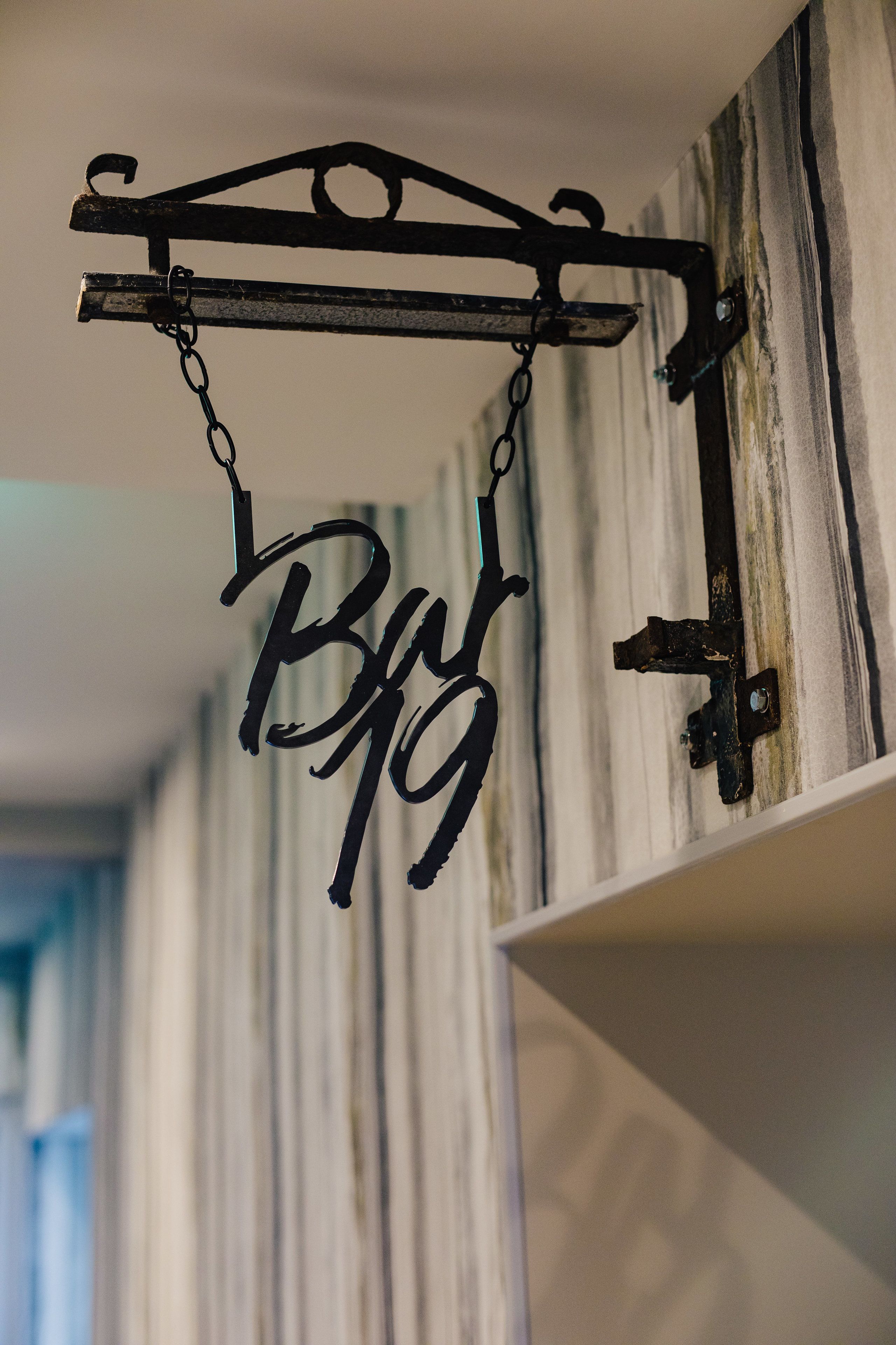 Ein Metallschild mit dem Schriftzug 'B&B', das an einer Deckenleuchte hängt.