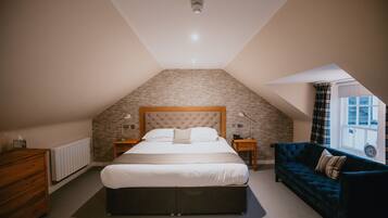 Un dormitorio con una cama grande, un aparador de madera, un sofá azul oscuro y una pared con diseño de piedra.