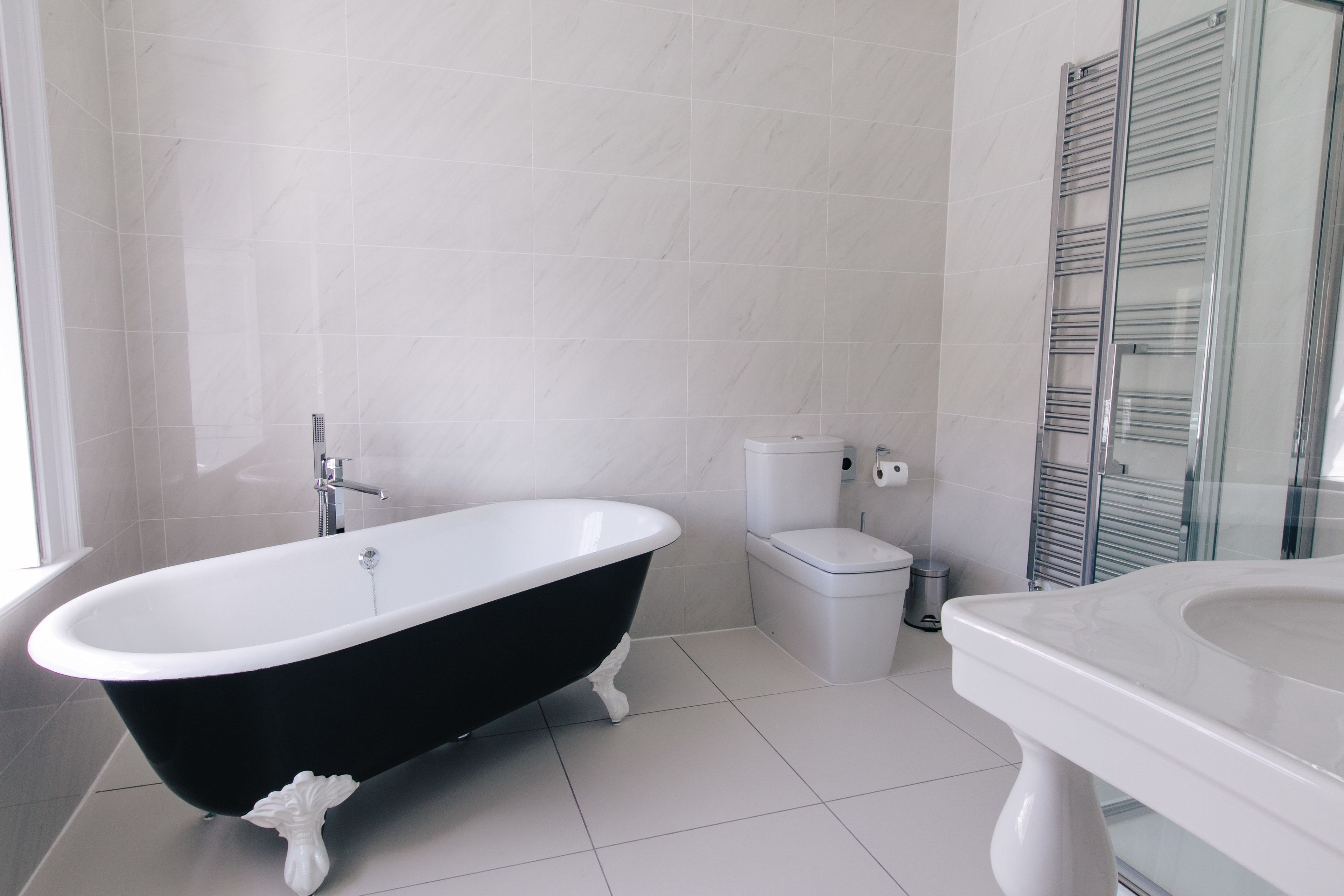 Une salle de bain avec une baignoire noire et blanche, des toilettes et une cabine de douche en verre.
