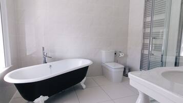 Une salle de bain avec une baignoire noire et blanche, des toilettes et une cabine de douche en verre.