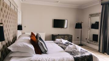 A hotel room with a large bed, a television, a mirror, and a radiator.