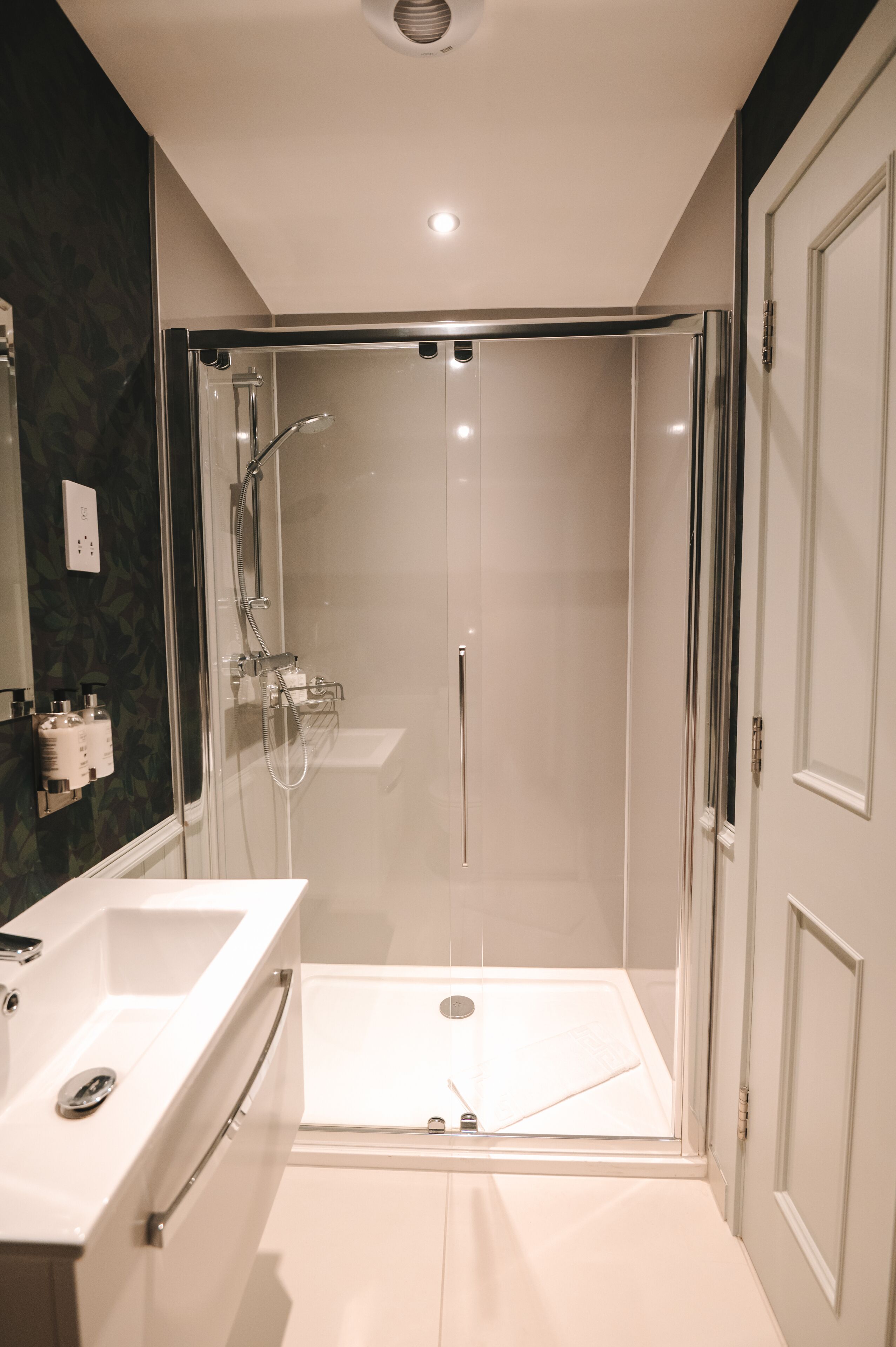 A modern bathroom with a glass-enclosed shower, a white sink, and a mirror.