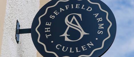 Un letrero circular con el texto "The Seafield Arms Cullen" colocado en un edificio.