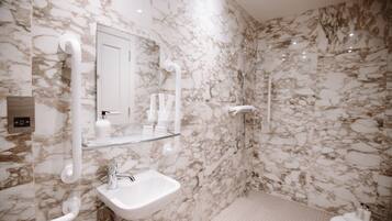 A bathroom with a marble wall, a sink, a mirror, and a shower.