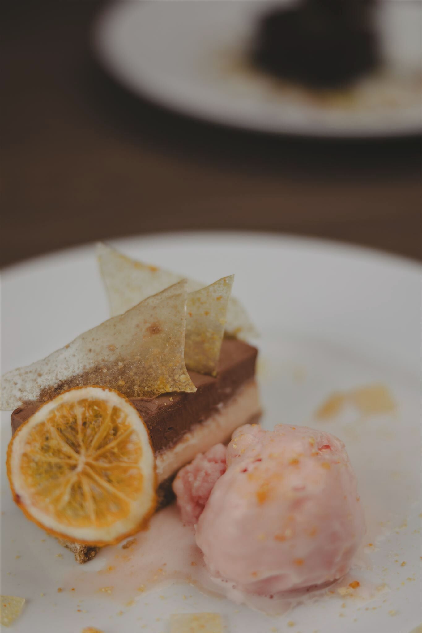 A dessert plate with a slice of cake, a scoop of ice cream, and a citrus slice.