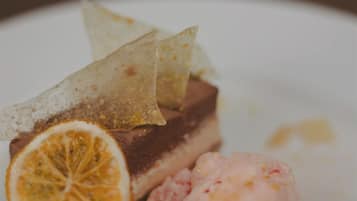 En desserttallrik med en bit tårta, en skopa glass och en citronskiva.