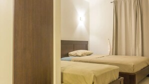 A room with two beds, a wooden headboard, and a light fixture on the wall.