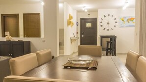 A dining area with a wooden table, beige chairs, a glass bowl, and a world map on the wall.