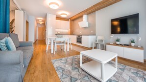 A modern living room with a grey sofa, a white coffee table, and a patterned rug. - Apartamenty Sun & Snow Jelitkowska (Gdansk)