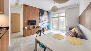 A modern kitchen with a dining area, a flat-screen TV, and a large window with curtains. - Apartamenty Sun & Snow Jelitkowska (Gdansk)