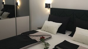 Un dormitorio moderno con un espejo grande, una cama con ropa de cama blanco y negro, y una lámpara de pared.