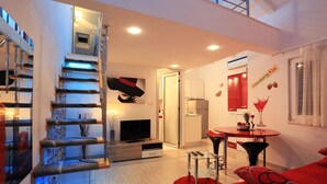 Una sala de estar moderna con una escalera, un televisor de pantalla plana, un comedor y una cocina.