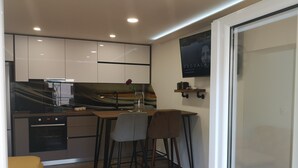 Una cocina moderna con armarios blancos, encimera negra y un comedor con dos sillas.