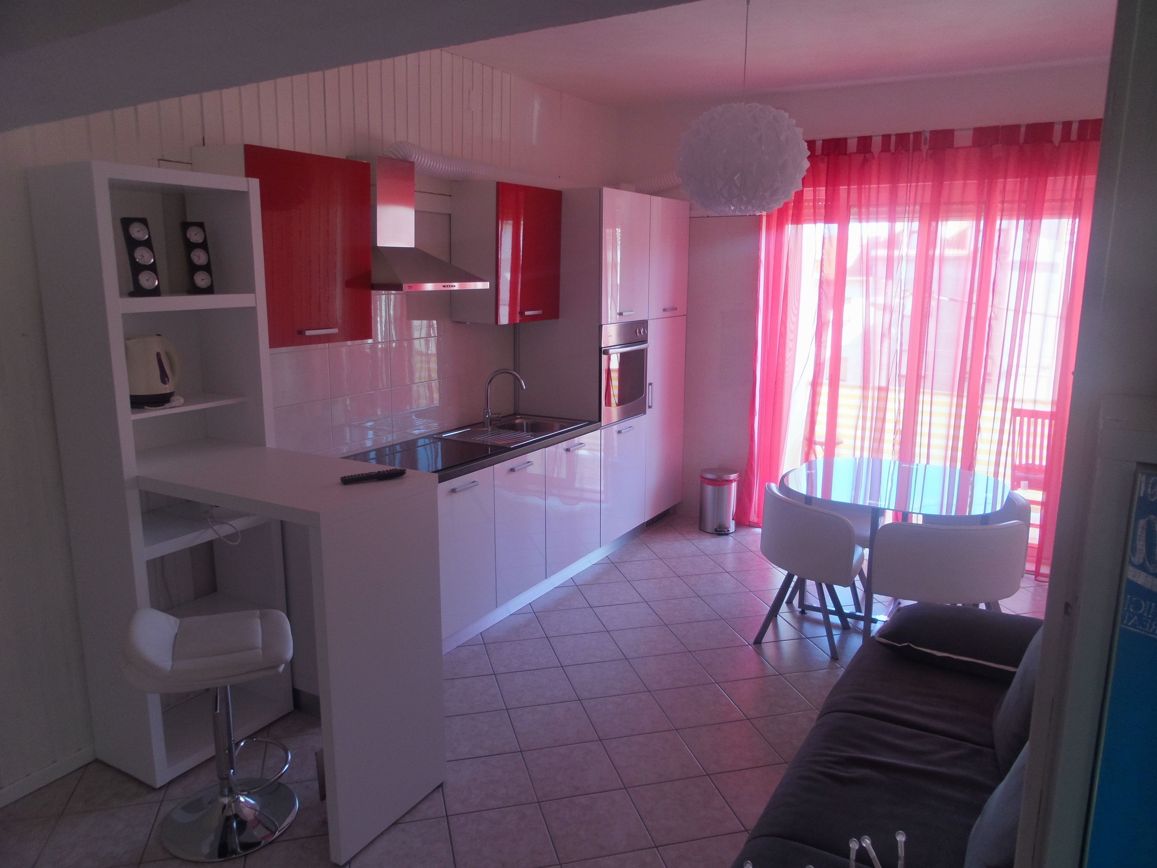 Une cuisine moderne avec des meubles blancs, un îlot central et un coin repas comprenant une table et des chaises.