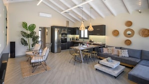 A modern kitchen with a dining area, featuring a high ceiling with exposed beams, pendant lighting, and a central island. - Sun Ray Beach life Villa (Chania)