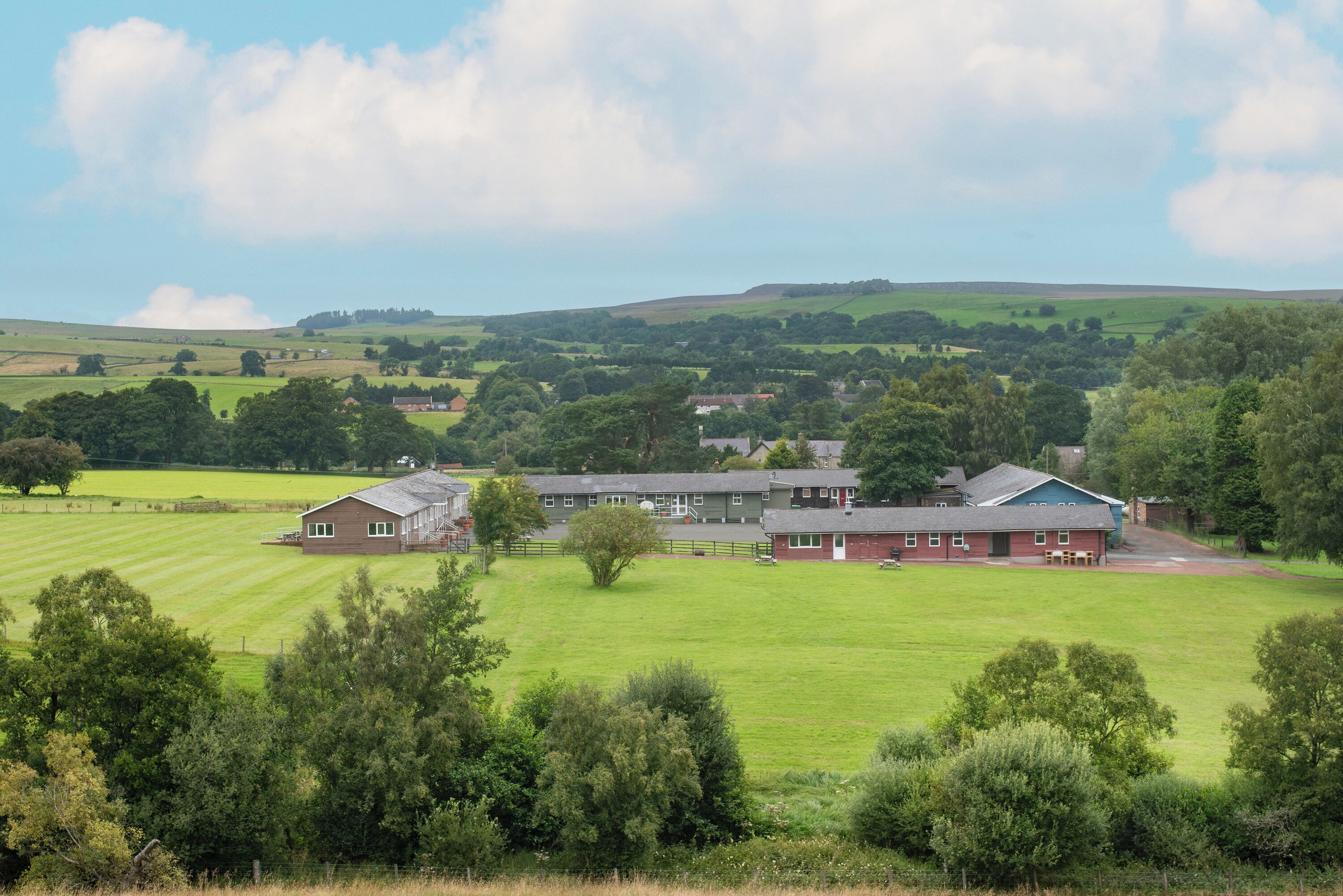 A rural property with multiple buildings, including a large house with a red roof and a smaller structure with a grey roof.