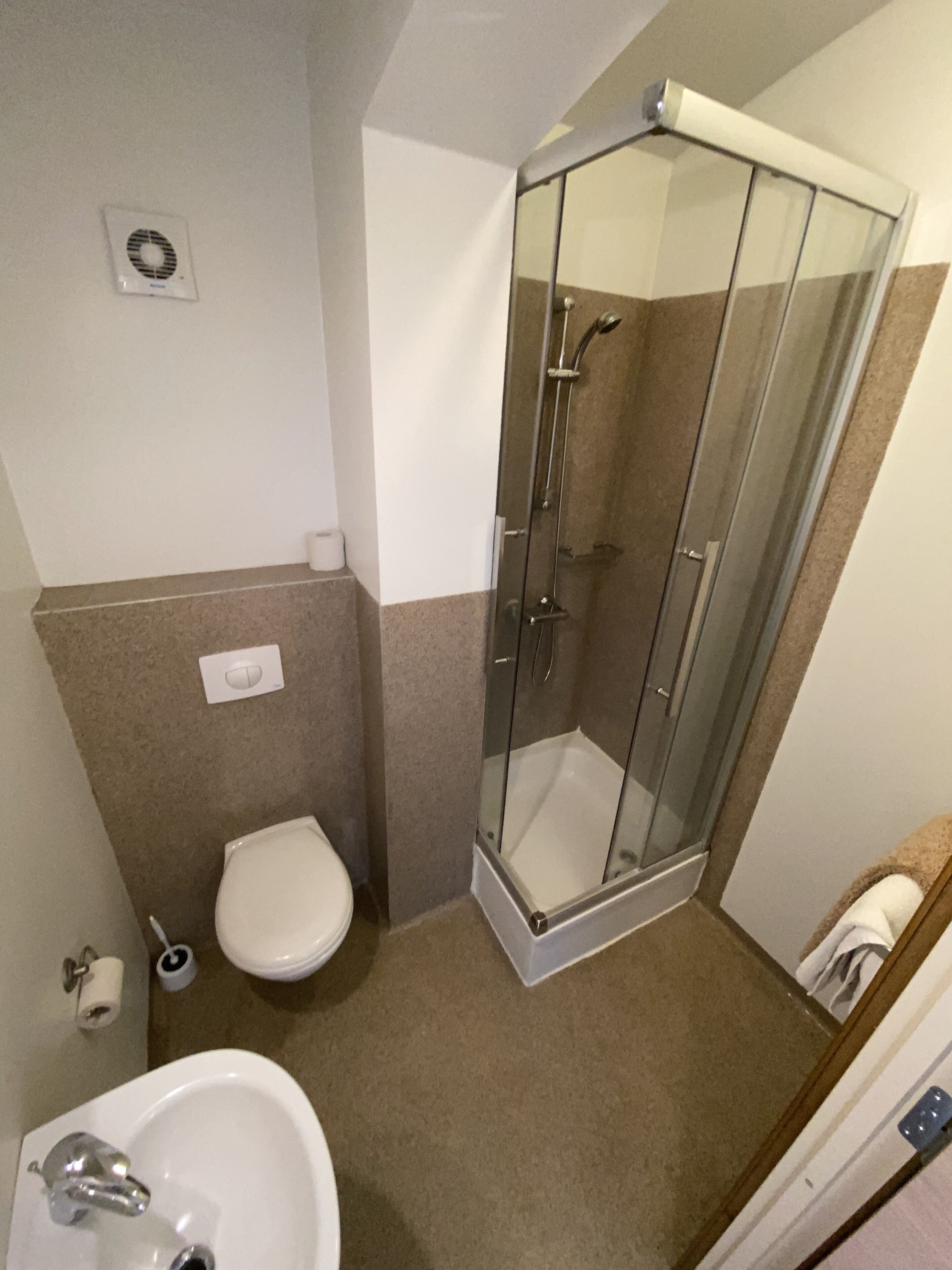 A bathroom with a glass-enclosed shower, a toilet, and a sink.