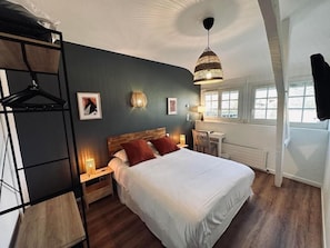 A bedroom with a bed, bedside tables, a hanging light fixture, a desk, and a chair. - Logis Hotel La Promenade (Coings)