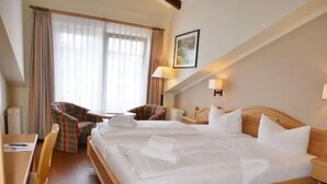Una habitación de hotel con una cama grande, dos sillones, una mesita y un escritorio.
