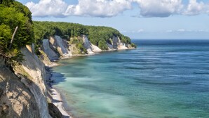 Un paisaje costero con acantilados, una playa y cielo despejado.