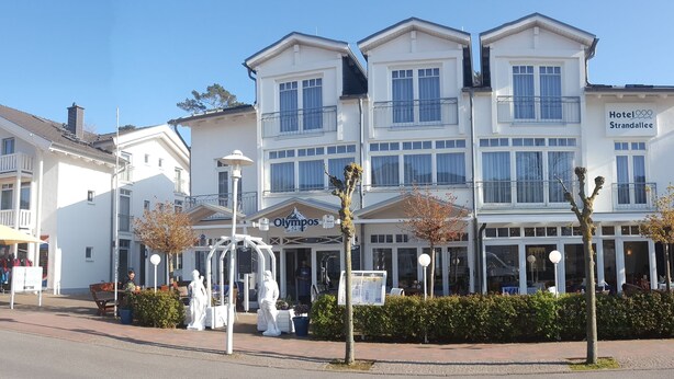 Un hotel con fachada blanca, balcones y un letrero que dice 'Hotel Strandallee'.