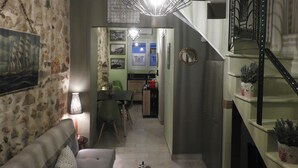 A cozy living room with a stone wall, a sofa, a table, and a staircase. - Cozy House Parga (Parga)
