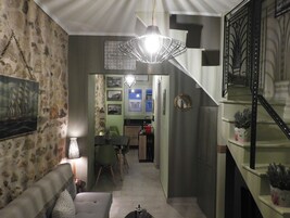 A cozy living room with a stone wall, a sofa, a table, and a staircase.