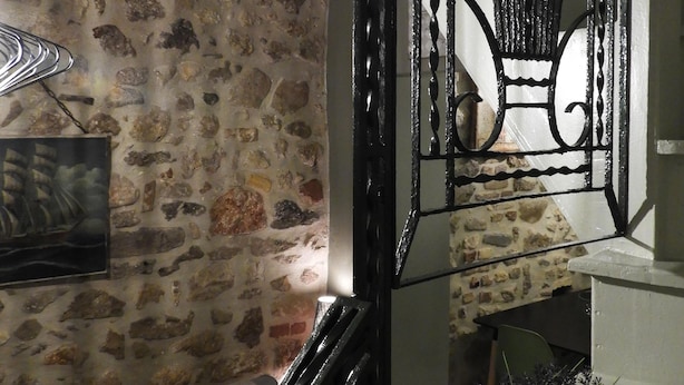 A staircase with a metal railing, a stone wall with a picture frame, and a potted plant. - Cozy House Parga (Parga)