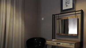 A hotel room with a bed, a desk with a mirror, a chair, and a wall-mounted air conditioner. - Cozy House Parga (Parga)
