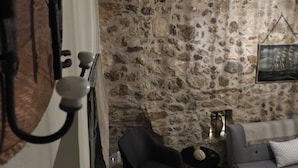 A room with a stone wall, a sofa, a small table with a vase, and a painting on the wall. - Cozy House Parga (Parga)
