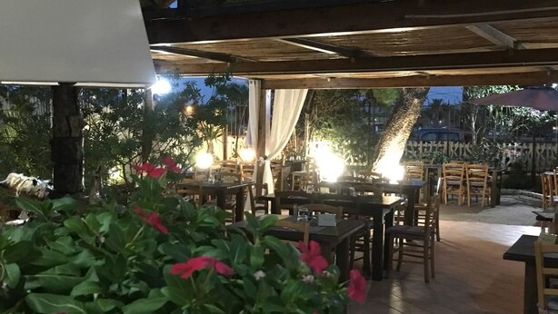 An outdoor patio area with tables and chairs, surrounded by greenery and trees. - La Medusa (Sant'Anna Arresi)