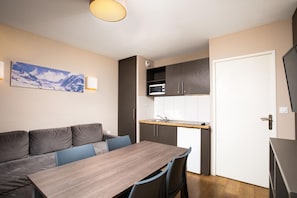 A compact kitchen with a microwave, a sink, and a dining area with a table and chairs. - Sowell Residences Pra Loup (Uvernet-Fours)